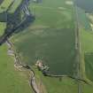 Oblique aerial view centred on the cropmarks of the rig and pits with the farmhouse and farmsteading adjacent, taken from the WSW.