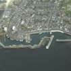 Oblique aerial view centred on the harbour, harbour basin, beacon, pier and jetties, taken from the NW.