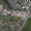 Oblique aerial view centred on the whisky distillery during demolition with the cemetery adjacent, taken from the SE.