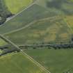 Oblique aerial view centred on the cropmarks of the unenclosed settlement and pits with the gate lodge and dismantled railway adjacent, taken from the NNE.