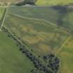 Oblique aerial view centred on the cropmarks of the unenclosed settlement and pits with the gate lodge and dismantled railway adjacent, taken from the NW.