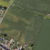 Oblique aerial view centred on the cropmarks of the enclosure and rig with the church adjacent, taken from the NW.