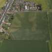 Oblique aerial view centred on the cropmarks of the enclosure and rig with the church adjacent, taken from the WSW.