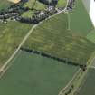 Oblique aerial view centred on the cropmarks of the barrows with the church adjacent, taken from the NE.