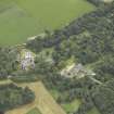 Oblique aerial view centred on the country house, stables and bridge, taken from the NW.