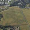 Oblique aerial view centred on the cropmarks of the settlement and fort with the church adjacent, taken from the N.