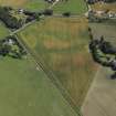 Oblique aerial view centred on the cropmarks of the enclosures and possible building with the manse and remains of the abbey adjacent, taken from the NW.