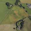 Oblique aerial view centred on the cropmarks of the enclosures and possible building with the manse, farmsteading, farmhouse and remains of the abbey adjacent, taken from the WSW.