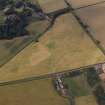 Oblique aerial view centred on the cropmarks of the field boundary and the cropmarks of the quarry with the farmhouse, farmsteading, country house, walled garden and dovecot adjacent, taken from the S.