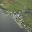 Oblique aerial view of the village centred on the whisky distillery and pier, taken from the ENE.