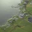 Oblique aerial view of the village centred on the whisky distillery and pier, taken from the NNW.