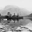 View of pier and buildings with Ben Nevis in the background. 
Titled: 'Ben Nevis from Corpach'
