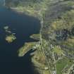 Oblique aerial view of the village centred on the harbour, slate quarries and remains of the fort, taken from the NNW.