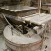 Interior. First floor. View of shelling stones, 'vat' or wooden jacket holding the stones, hopper and grain feeding apparatus.