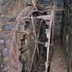 Interior. View of enclosed wheelpit looking towards launder. Note the rim gearing on the waterwheel.