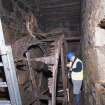 Interior. Waterwheel pit. View of J Borland of RCAHMS undertaking graphic survey. The small driven gear visible.