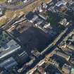 Oblique aerial view centred on the cleared Caltongate development site (former SMT bus garage) with Canongate adjacent, taken from the SW.