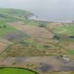 General oblique aerial view looking across the cropmarks of the barrows, pits, field boundaries and enclosure at West Myroch towards Port Logan, taken from the ENE.