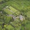 Oblique aerial view of the tower house with the gardens and stables adjacent, taken from the SW.
