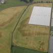 Oblique aerial view centred on the cropmarks of the rig, pits, enclosure, round house and souterrains at Hatton Farm, taken from the WNW.