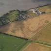 Oblique aerial view of the cropmarks of the round houses and ring ditches of the unenclosed settlement at Newbigging, taken from the NE.