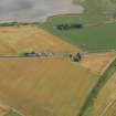 Oblique aerial view centred on the cropmarks of the Roman Temporary Camp, ring ditches, round houses and rig and furrow at Dun, taken from the NE.