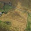 Oblique aerial view of the cropmarks of the barrow, ring ditches and pits at Easter Kinnear with the farmsteading adjacent, taken from the SE.