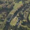 Oblique aerial view centred on the ruins of the country house with the stables adjacent, taken from the NNE.