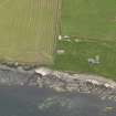 Oblique aerial view centred on the coastal gun battery with the remains of the broch adjacent, taken from the  NNW.