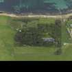 Oblique aerial view centred on the house with the remains of the chambered mound adjacaent, taken from the NE.