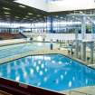 Interior view of Royal Commonwealth Pool, Edinburgh. Elevated view from spectator seating banks, looking W across diving pool towards main competition pool.