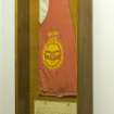 Interior, wooden glass fronted wall case with 821 Squadron pennant.