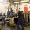 Interior. Cask Rebuild Process. Jamie O' Hare, a cooper for 41 years, building or 'rising' a cask. The cask is being turned manually for the tightening process to be carried out on the other end of the cask.