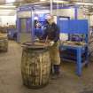 Interior view of Cask Rebuild Process, Dundashill Cooperage, Glasgow. Chapping Out Area. The cooper putting on the first of four temporary truss hoops prior to removal of both end hoops.