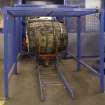 Interior.  Cask Rebuild Process. Croze Machine. A chapped out, trimmed and cut  cask shell with its four temporary truss hoops leaving the croze machine. Note the next cask about to have its crozes cut and chimes trimmed in the background.