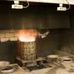 Interior. Cask Rejuvination Process. Charring Area. The gas jet burners. The cask shells to be rejuvinated were placed on movable plates with a circular flange to hold the shell steady. This was slid into place by compressed air and the jet gas burners set alight and the interior of the cask was burnt for about two and a half minutes. Charring carmelises the sugars in the wood and allows the cask to impart colour and flavour into the spirit as it undergoes maturation in the cask..