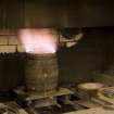 Interior. Cask Rejuvination Process. Charring Area. The gas jet burners. The cask shells to be rejuvinated were placed on movable plates with a circular flange to hold the shell steady. This was slid into place by compressed air and the jet gas burners set alight and the interior of the cask was burnt for about two and a half minutes. Charring carmelises the sugars in the wood and allows the cask to impart colour and flavour into the spirit as it undergoes maturation in the cask..