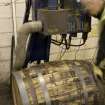 Interior. Cask Rebuilding Process. Bung Hole Borer. After the frist hoop drive, the operator centres the cask below the laser beam (visible) pinpoints where the drill will go. This machine has an extractor to remove the wood dust and shavings. The cask is still warm from charring (rejuvination) or steaming (rebuild) at this point.