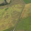 Oblique aerial view of the cropmarks of the barrow, unenclosed round houses, pits and rig, taken from the W.