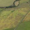 Oblique aerial view of the cropmarks of the barrow, unenclosed round houses, pits and rig, taken from the WSW.