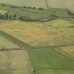 Oblique aerial view of the cropmarks of the barrow, unenclosed round houses, pits and rig, taken from the SW.