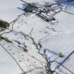 Oblique aerial view of building, quarries, lynchets and rig and furrow under snow, looking to ENE.