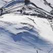 General oblique aerial view of scooped settlement, settlement and cultivation terraces under snow, looking to WSW.