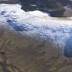 General oblique aerial view of fort, settlement, enclosures, track and cultivation terraces under snow, looking ESE.