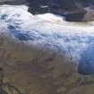 General oblique aerial view of fort, settlement, enclosures, track and cultivation terraces under snow, looking ESE.