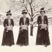View of three ladies dressed in matching coats and handwarmers in the snow.

