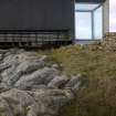 View of the Northern end of the East elevation of An Turas waiting room, Tiree. The image shows the structure straddling the rocky terrain.