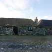 View of the East elevation of the thatched cottage and adjoining building at 13 Kilmoluaig, Tiree.