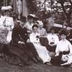 View of group of people sitting in garden.
Titled: 'Aikenshaw July 1905. Miss Louise Stuart, Miss Grant, Mr Parker, Miss Parker, Francess, Mrs Jameson, Miss Davidson, Jessie, Mr W S Turnbull, Stroncher'. 
PHOTOGRAPH ALBUM No.21: CYCLE TOUR ALBUM.
