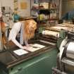 View of student working on a press within the case room of the Foulis Building